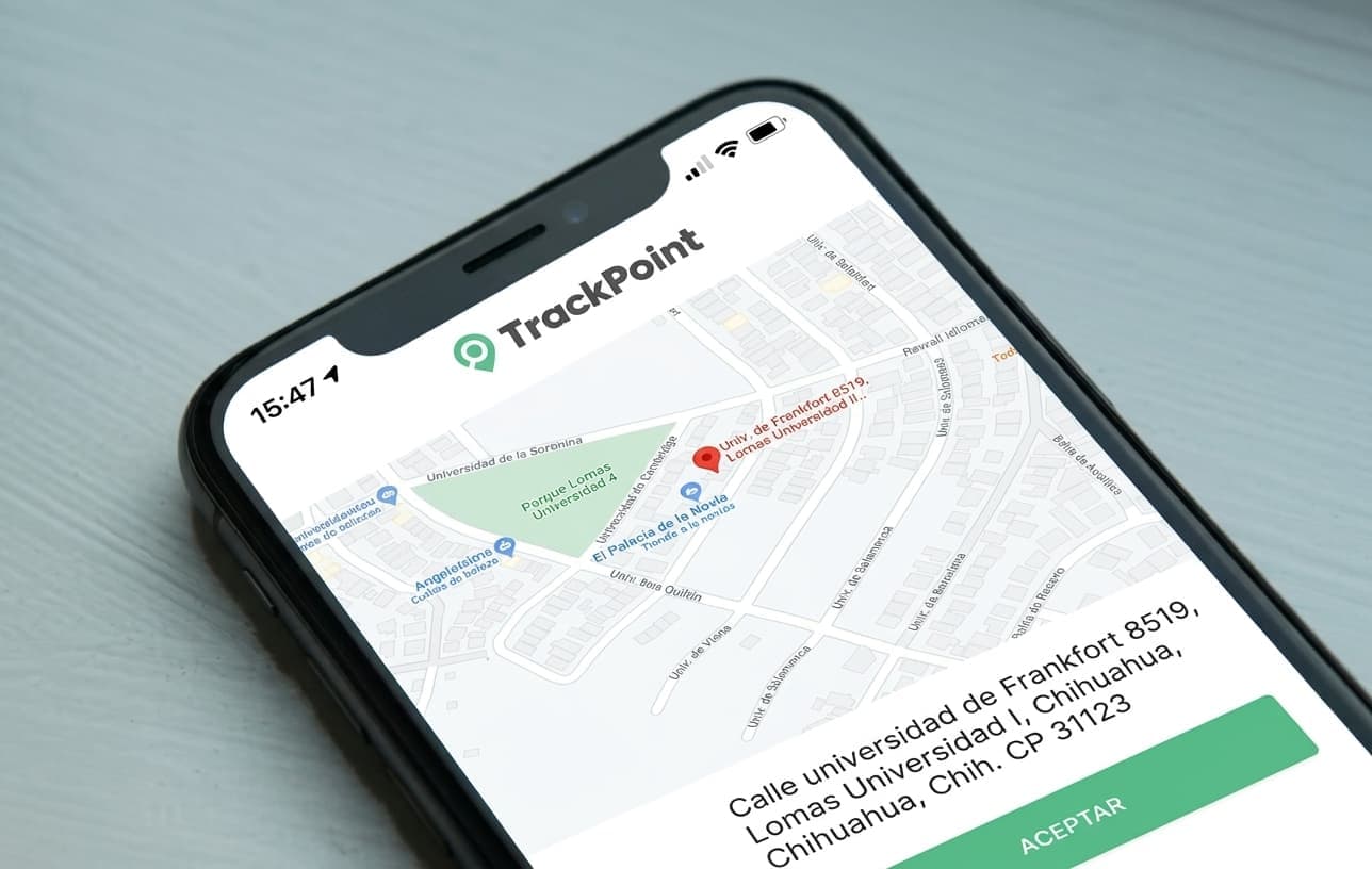 Teléfono sobre un escritorio con la app de TrackPoint abierta en la pantalla de ubicación de una visita