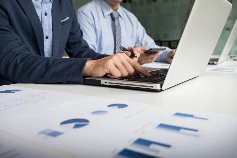 Dos personas empresarias frente a una computadora revisando gráficas de ROI